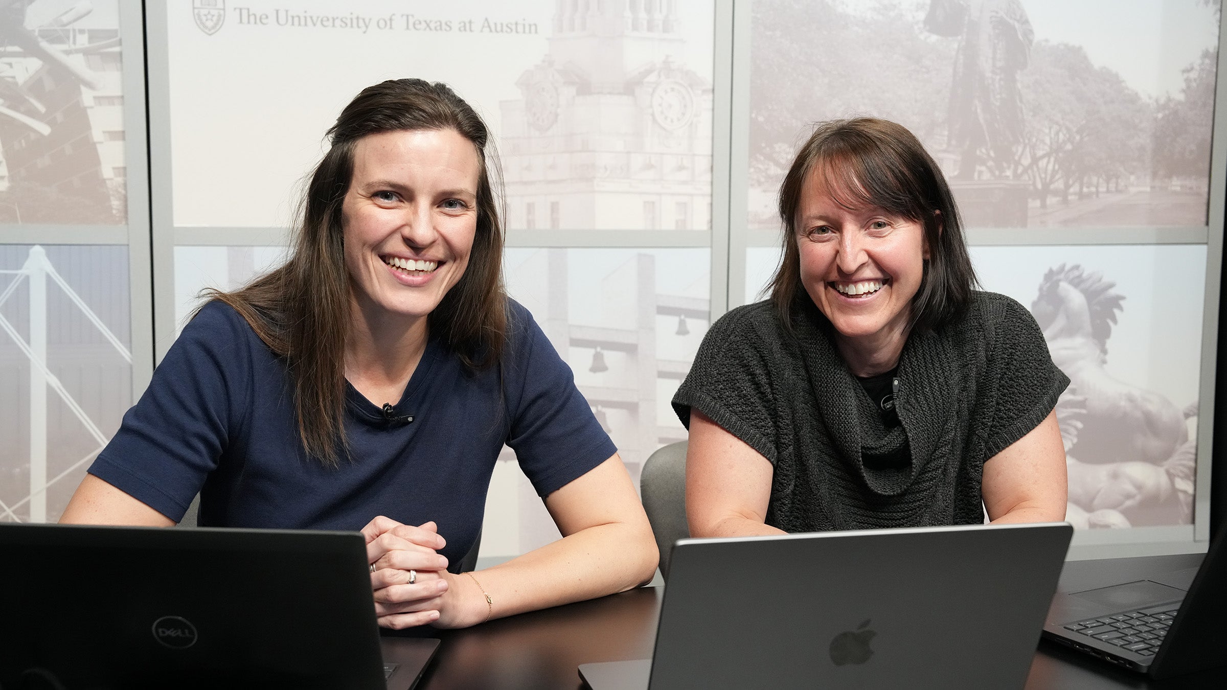 Two women with brown hair sit in a video studio side by side